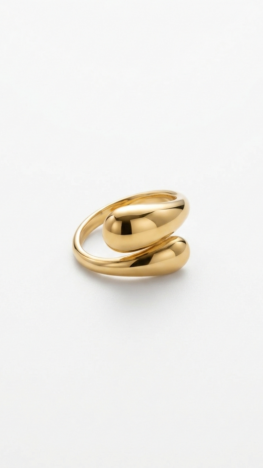 A bold 18K gold-plated bypass ring featuring two polished teardrop motifs on a woman's hand against a white background.