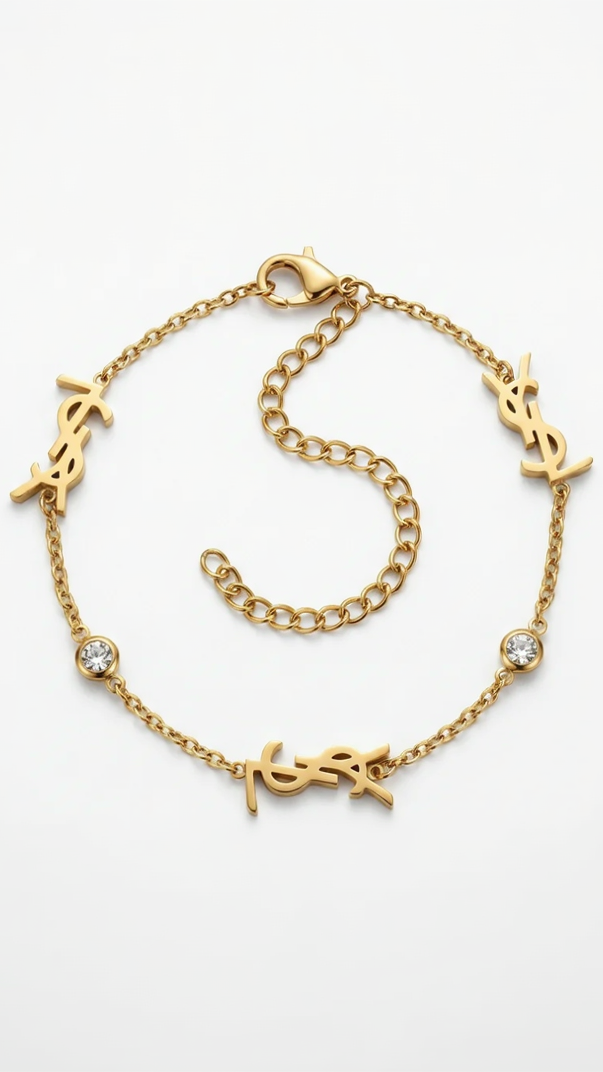 A dainty 18K gold-plated cable chain bracelet with three gold monogram charms and two bezel-set crystals on a white background.