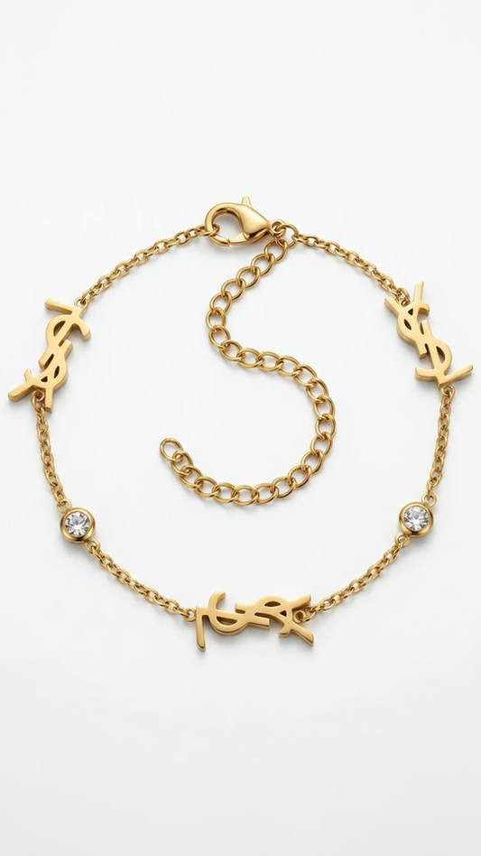 A dainty 18K gold-plated cable chain bracelet with three gold monogram charms and two bezel-set crystals on a white background.