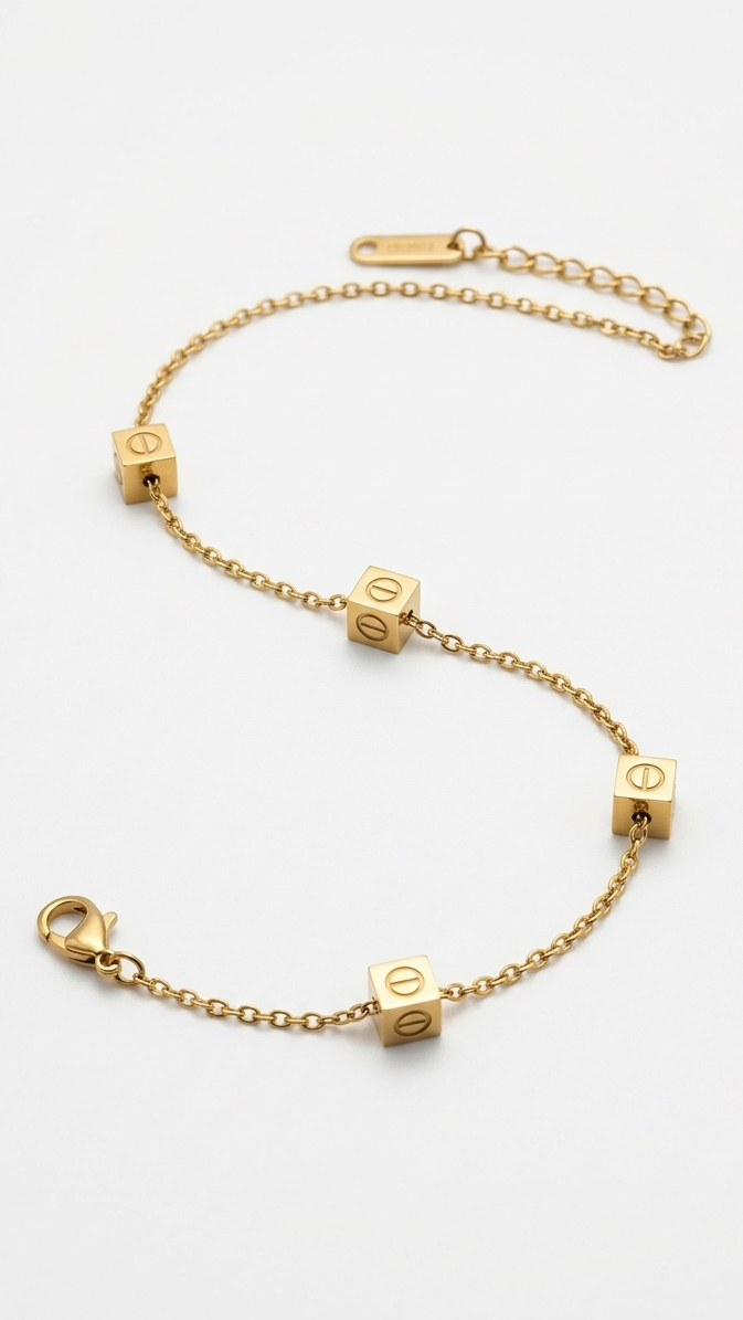 A dainty 18K gold-plated chain bracelet featuring four gold cubes with etched screw-head motifs on a model's wrist.