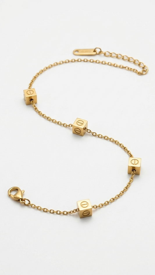 A dainty 18K gold-plated chain bracelet featuring four gold cubes with etched screw-head motifs on a model's wrist.