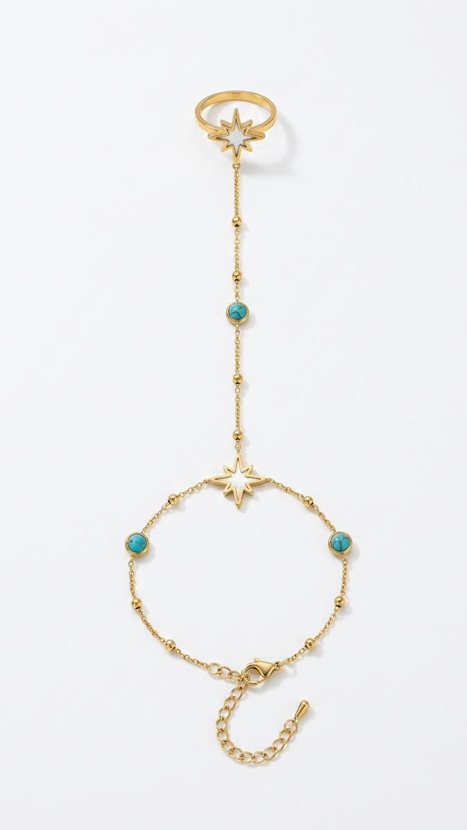 A dainty 18K gold-plated hand chain with white enamel North Star motifs and turquoise-colored stones on a model's hand.
