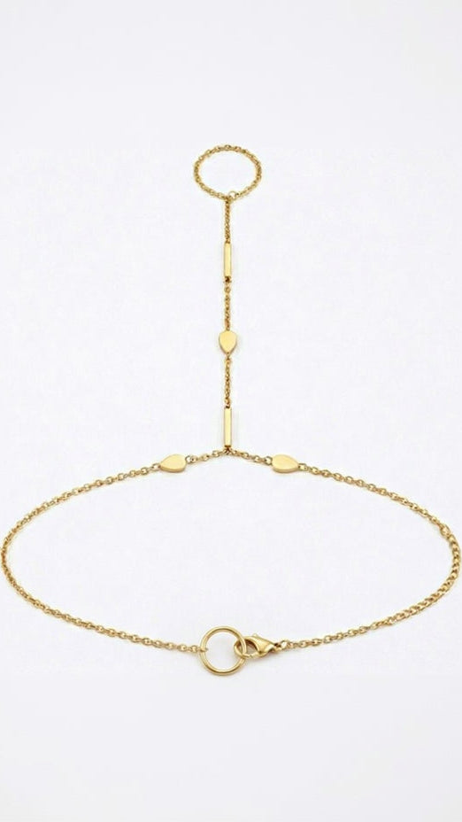 A delicate 18K gold-plated hand chain featuring a ring connected to a bracelet by a thin chain with small bar and teardrop accents.