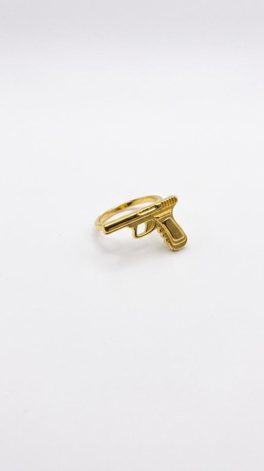A detailed 18K gold-plated ring featuring a 3D sculpted pistol motif on a polished slim gold band.