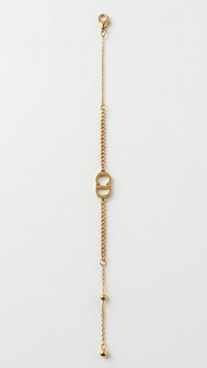A minimalist 18K gold-plated bracelet featuring a central CD logo on a fine curb chain worn on a model's wrist
