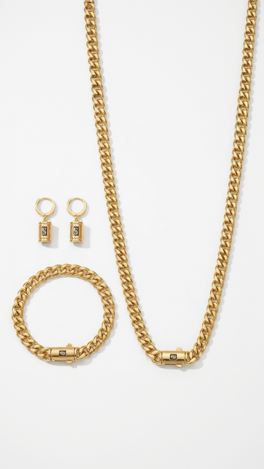 A model wearing a complete 18K gold-plated jewelry set consisting of a thick curb chain necklace, matching bracelet, and cylindrical monogram drop earrings.