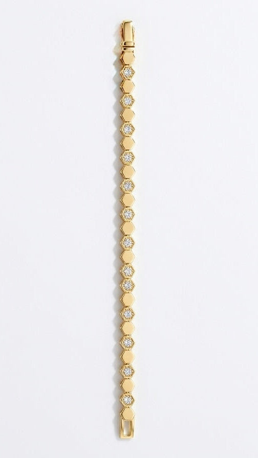 A modern 18K gold-plated tennis bracelet featuring an interlocking honeycomb design with shimmering pave crystals on a model's wrist.