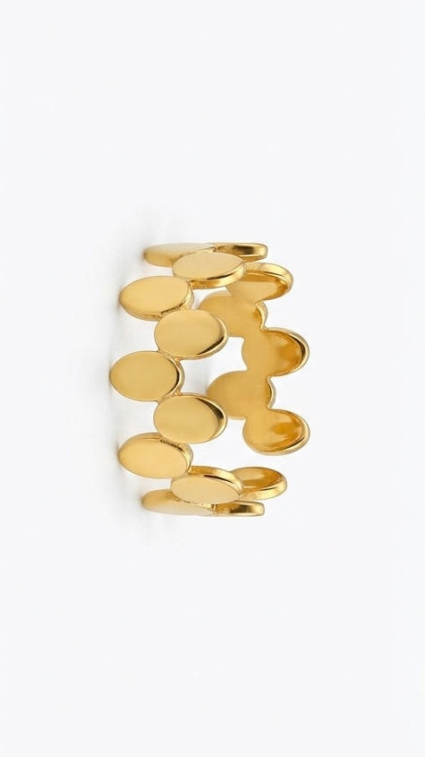 A polished 18K gold-plated eternity ring featuring a staggered pattern of linked oval shapes, shown on a model's hand.