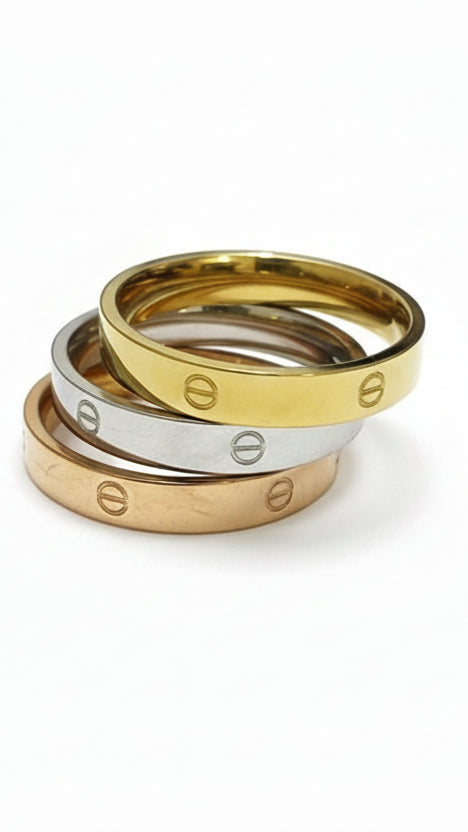 A stack of three 18K gold-plated rings in yellow gold, silver, and rose gold, each featuring an etched screw motif.