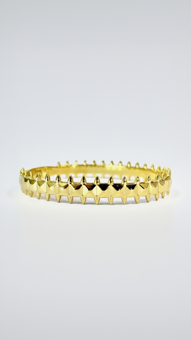 A structured 18K gold-plated bangle featuring a repeating 360-degree pattern of polished pyramid studs and spikes on a white background.