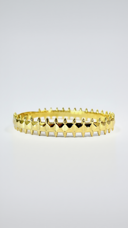 A structured 18K gold-plated bangle featuring a repeating 360-degree pattern of polished pyramid studs and spikes on a white background.
