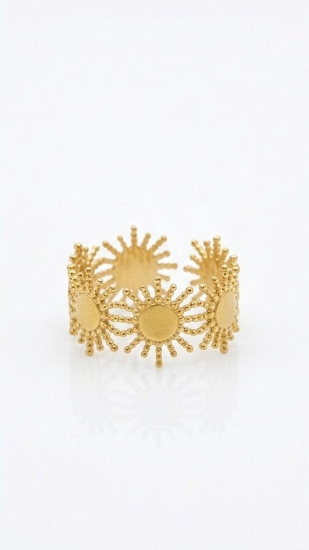 A wide 18K gold-plated band ring with a matte finish, featuring an open-work sunburst and solar ray design on a white background.