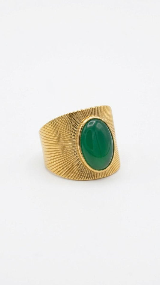 A wide 18K gold-plated signet ring featuring a large oval green stone and a radial sunburst engraved pattern on the band.