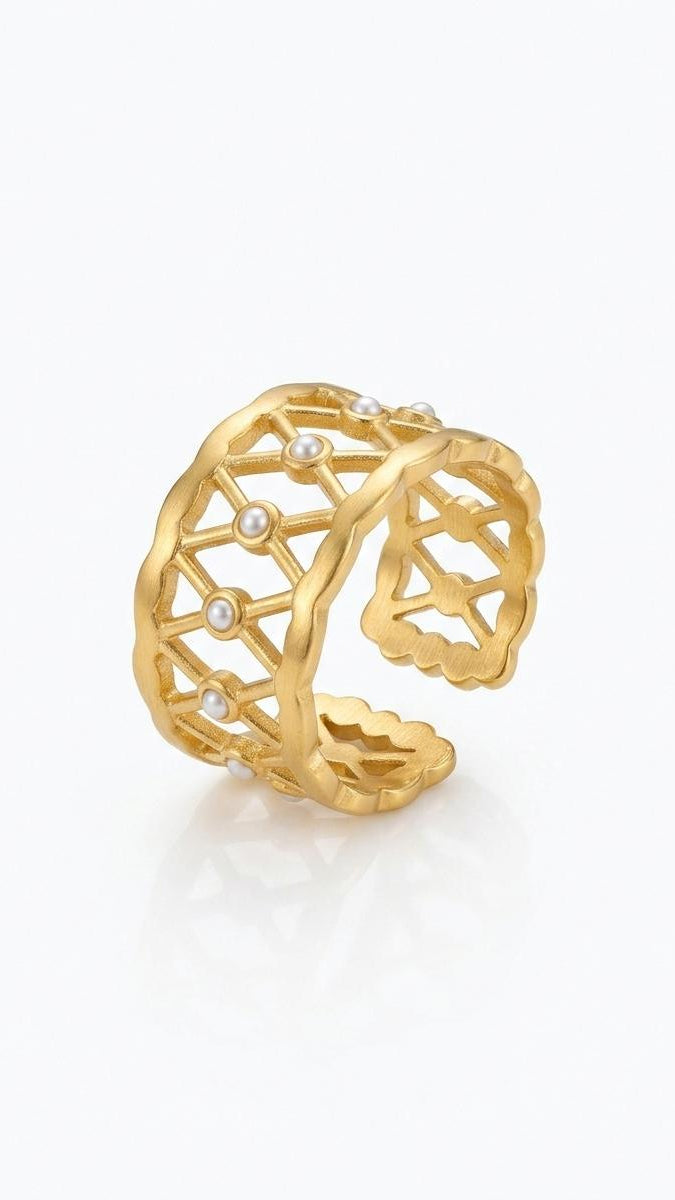 A wide matte 18K gold-plated lattice ring with small white pearls and a scalloped edge, shown on a model's hand and against a white background.