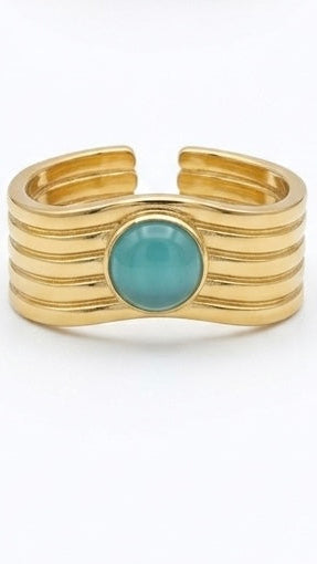 A wide, ribbed 18K gold-plated statement ring with a round, smooth blue gemstone in the center.