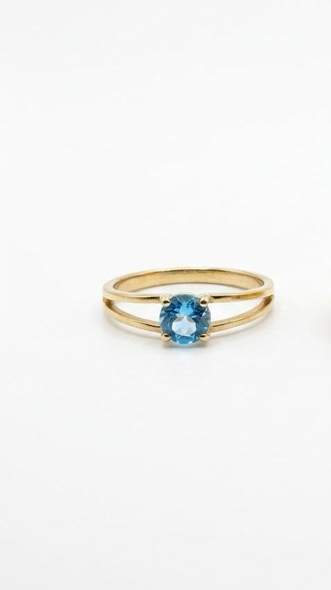A women's 18K gold-plated ring with a round blue gemstone held between a split-shank band.