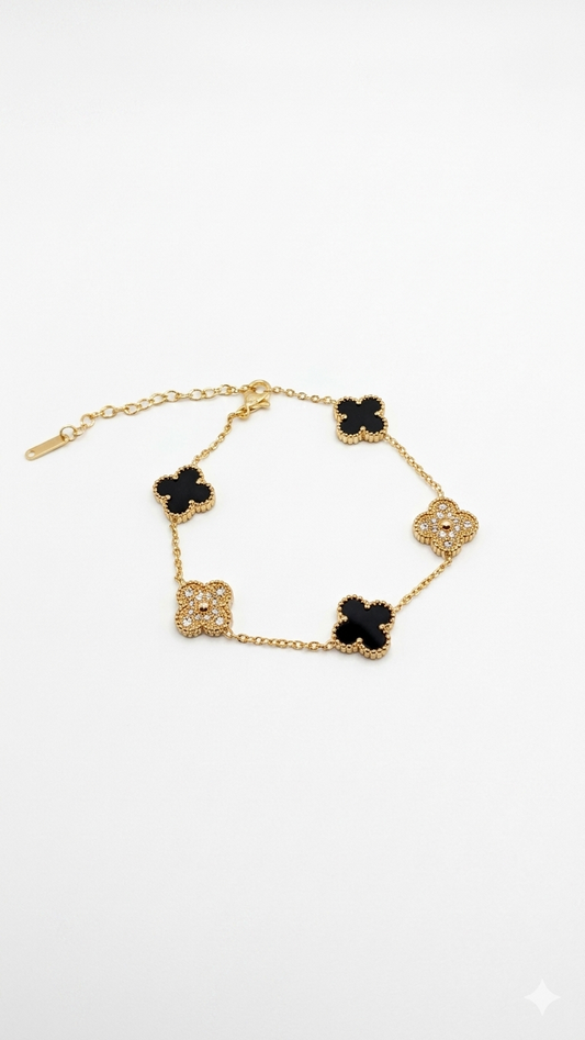 Gold bracelet with black clover-shaped charms on a white background