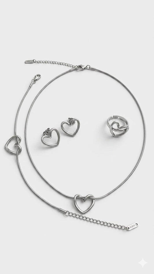 Presteige Accessories complete silver bypass heart jewelry set on plain background.