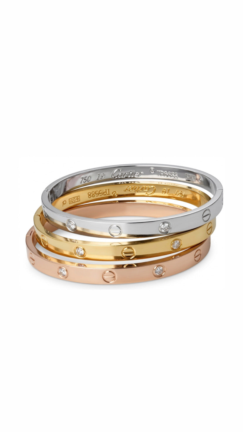 A stack of three bracelets featuring a gold presidential link chain, a silver presidential link chain, and a wide gold flat herringbone bracelet.